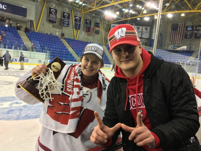 Wisconsin goaltender Kristen Campbell celebrates her 2019 NCAA Division I national championship on the glass with her brother, Kyle, at People's United Center. Kyle makes the signature Wisconsin "W" sign with his hands.